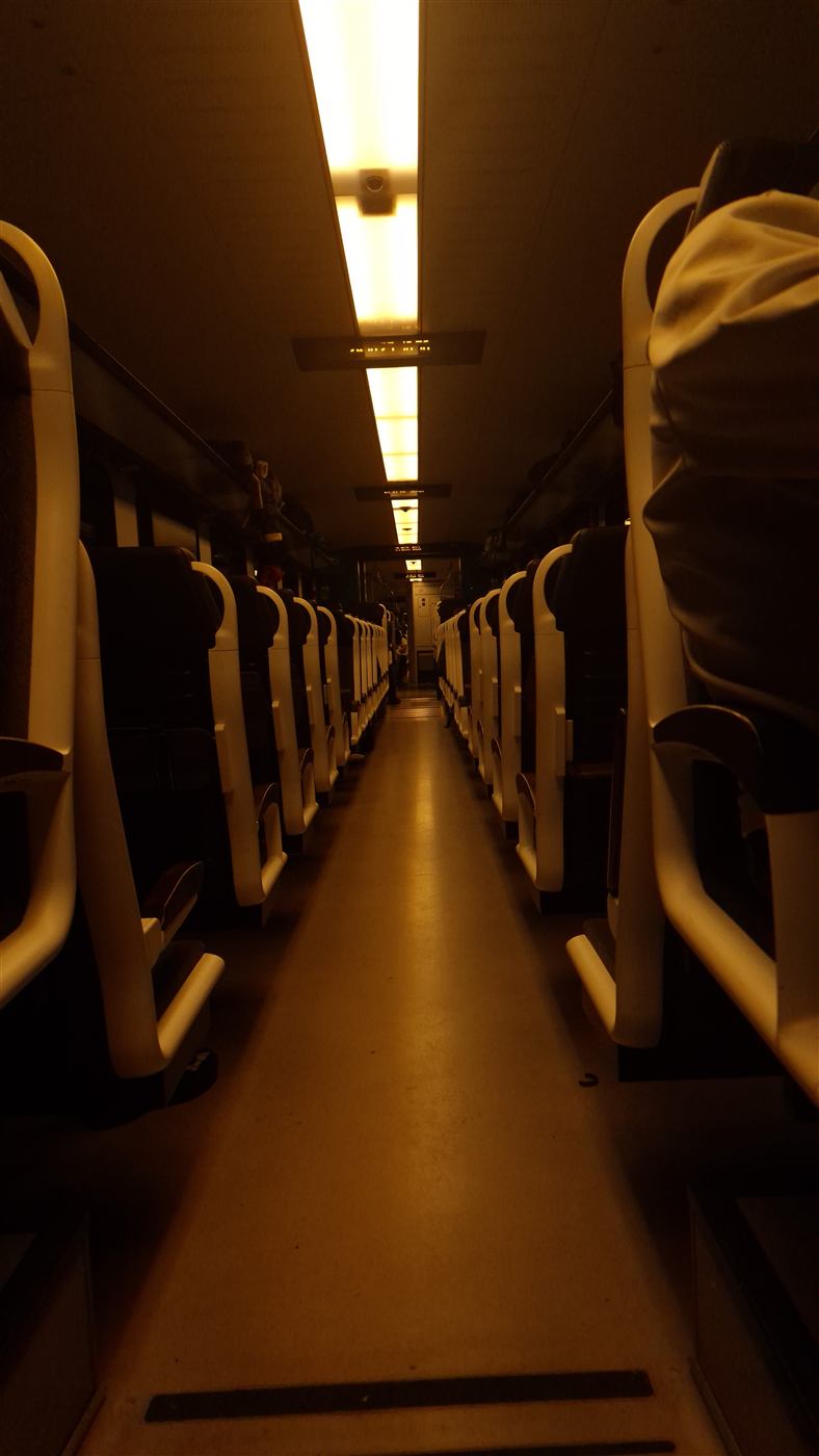 The long corridor of a night train, lit orange